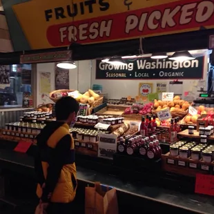 a woman standing in front of a fruit stand