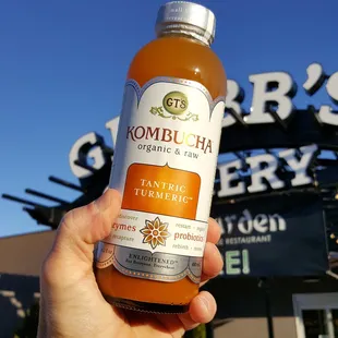 a hand holding a bottle of orange juice