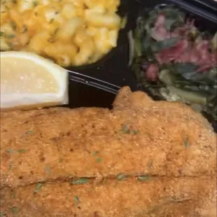 a meal of fish, macaroni and cheese, and a lemon wedge