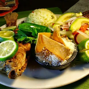 Tasty combination of whole deep fried tilapia and shrimp server with rice, beans and salad.