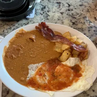 Huevos rancheros with over easy eggs, potato and egg breakfast plate and a side of bacon for the table.