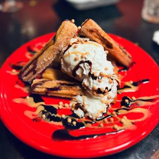 a red plate with waffles and ice cream