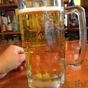 a person's hand holding a glass of beer