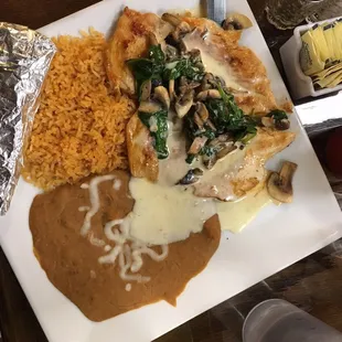 Popeye Chicken! Chicken breast covered in spinach, mushrooms and cheese sauce served with rice and beans.