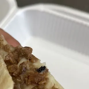 a hand holding a piece of pizza