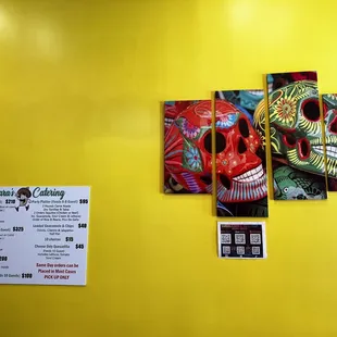 a yellow wall with three colorful skulls on it