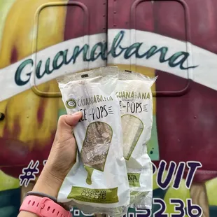 a hand holding a bag of guanabana