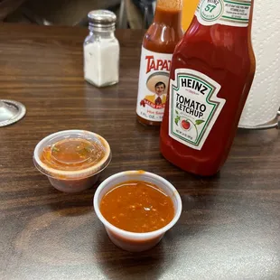 a bottle of ketchup and two small bowls of sauce
