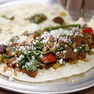 a person putting cheese on a tortilla