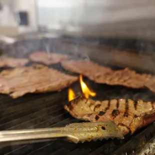 steaks cooking on a grill