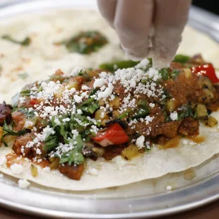 a person putting cheese on a tortilla