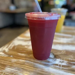 a red drink with a straw in a plastic cup
