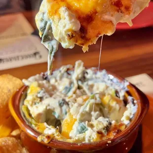 a hand holding a piece of cheese dip