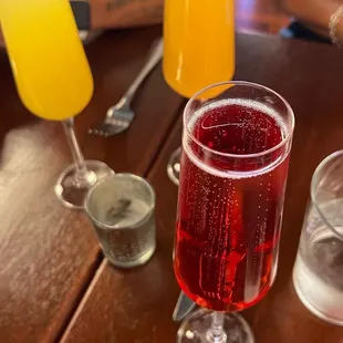 a glass of red wine and two glasses of orange juice