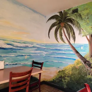 a table and chairs in front of a mural