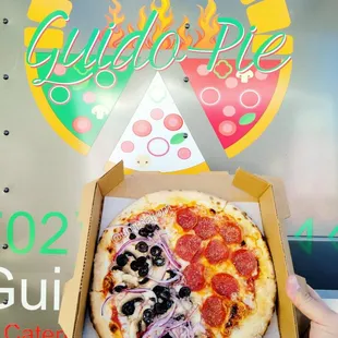 a hand holding a box of pizza