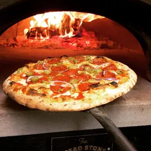 a pizza being cooked in a brick oven