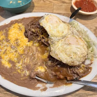 Sonoran Enchiladas with shredded beef and 2 over easy eggs on top