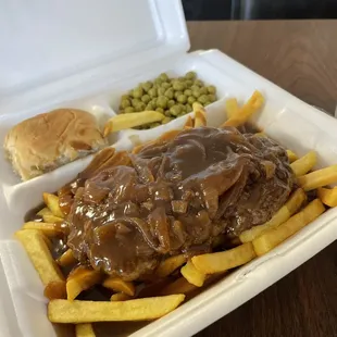 Hamburger steak dinner over fries.