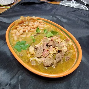 Carne en su jugo consists of slow-cooked beef strips with bacon and spring onions in a zesty, flavorful broth.