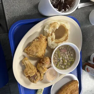 a plate of fried chicken, mashed potatoes, beans, and gravy