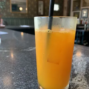 a glass of orange juice with a straw
