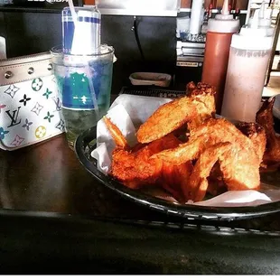 Gunnys wings with their signature sauce depicted next to the hot sauce and my favorite cocktail of theirs called the trash can. Yummy!