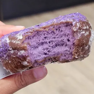 a hand holding a purple donut