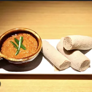 a bowl of soup and two rolls of bread