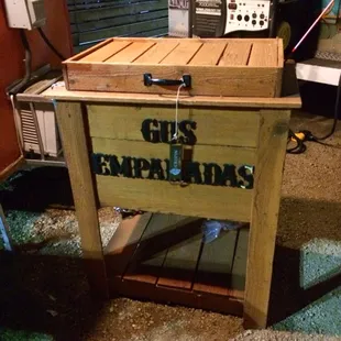  wooden cooler with a sign that says gus empanadas