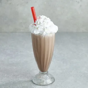 a milkshake with whipped cream and a red straw