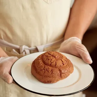 a person holding a plate with a pastry on it
