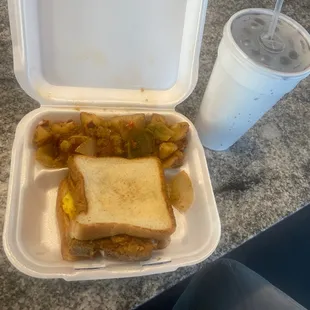 a sandwich and potatoes in a styrofoam container