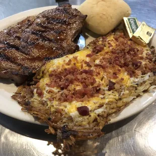 Ribeye with hash browns covered with cheese and bacon.