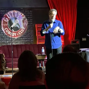 a man in a blue shirt and bow tie speaking into a microphone