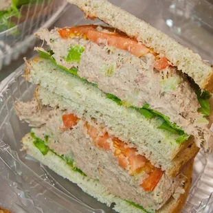 Tuna sandwich served on multigrain bread with lettuce, tomato, onions, arugula