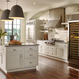 a kitchen with white cabinets and wood floors