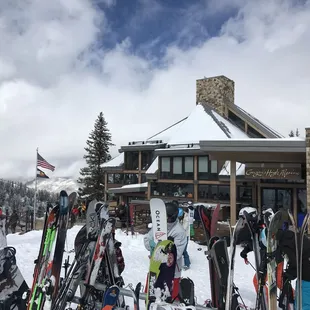 skis and snowboards in front of a lodge
