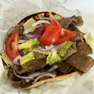a steak sandwich with lettuce, tomatoes, and onions