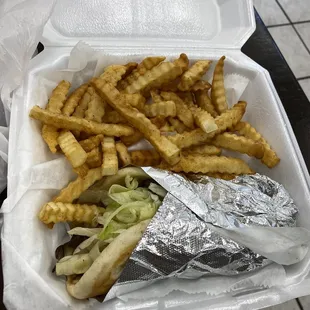 a sandwich and french fries in a styrofoam container