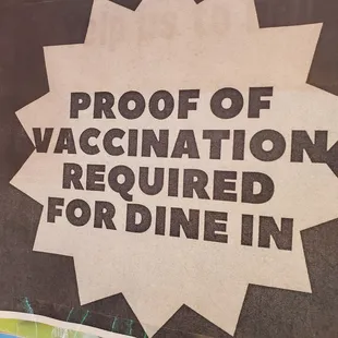 a sign that reads proof of vaccination required for dine in