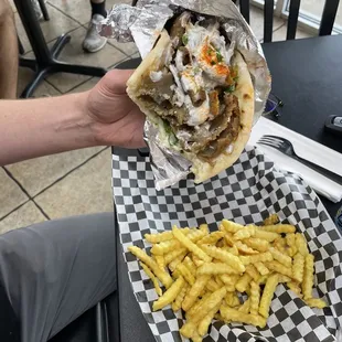 a person holding a sandwich and french fries