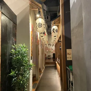 a narrow hallway with lanterns hanging from the ceiling