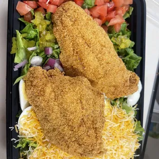 two chicken schnitzers on a bed of lettuce and tomatoes