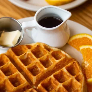 Delicious Belgian Waffle with orange slices, butter and maple syrup