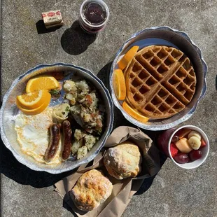 Classic breakfast with over medium eggs and chicken Apple sausages with biscuits  Waffles with fruit