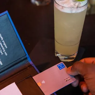 a person holding a credit card and a drink