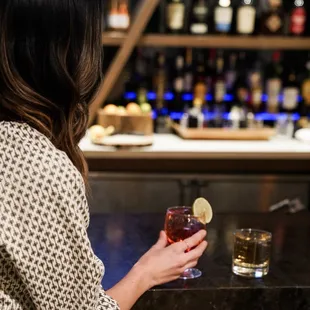 a woman sitting at a bar holding a drink
