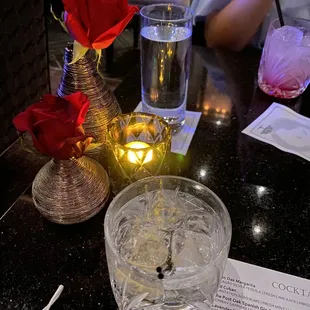 a glass of water with a red rose in it