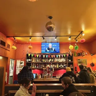 people sitting at a bar watching television